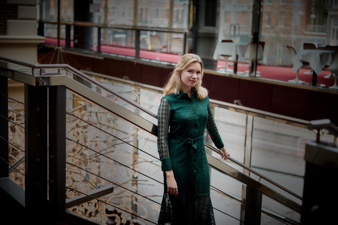 On a balcony overlooking the street, in a green dress
